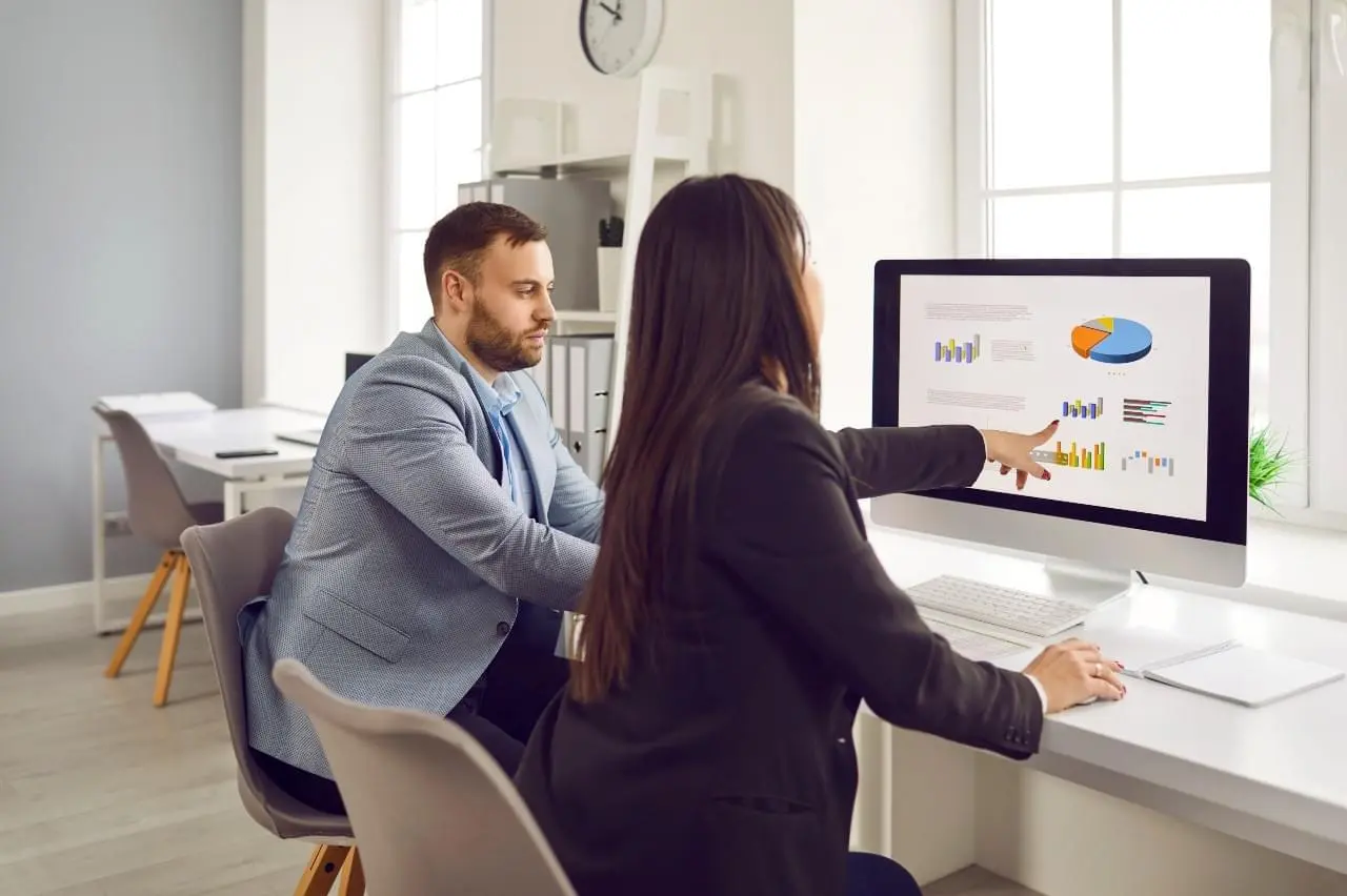 Management pointing at a desktop showing graphs